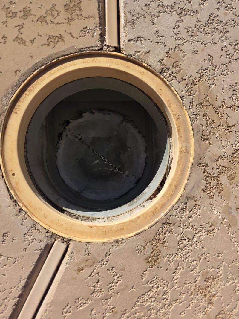 Close up of a round pool skimmer lid set into a stucco colored pool deck